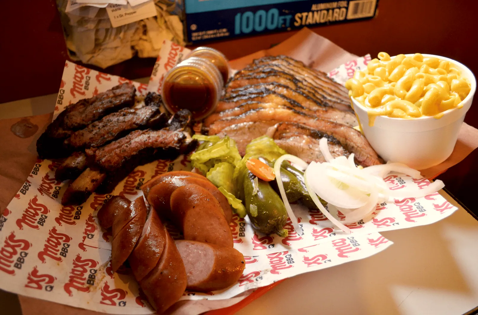 Charola completa de Max's BBQ con costillar, brisket rebanado, salchicha ahumada y mac n' cheese