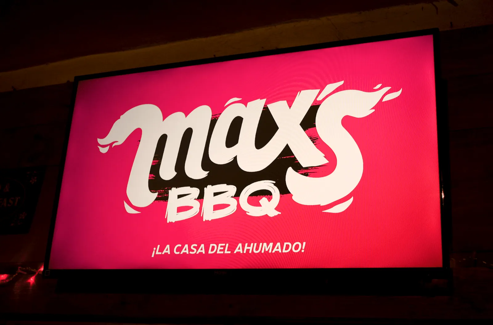 Pantalla iluminada con el logo de Max's BBQ y el lema ¡La casa del ahumado!