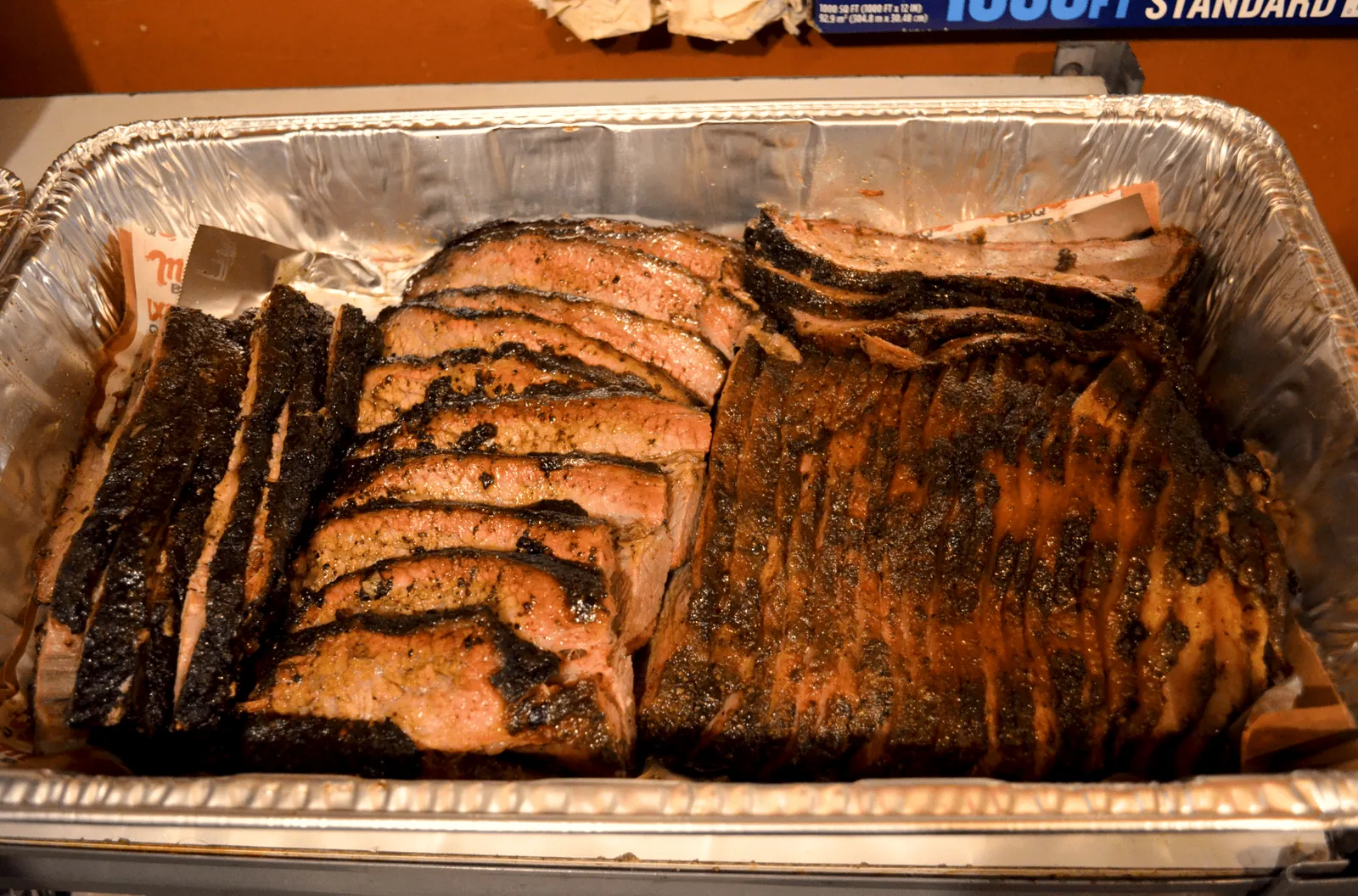 Bandeja de aluminio llena de brisket ahumado recién rebanado